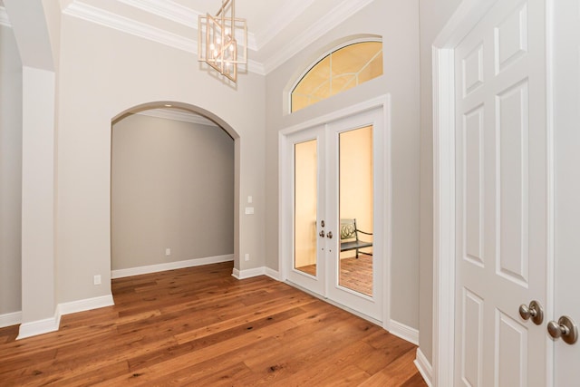 spare room featuring hardwood / wood-style flooring, a notable chandelier, ornamental molding, and french doors