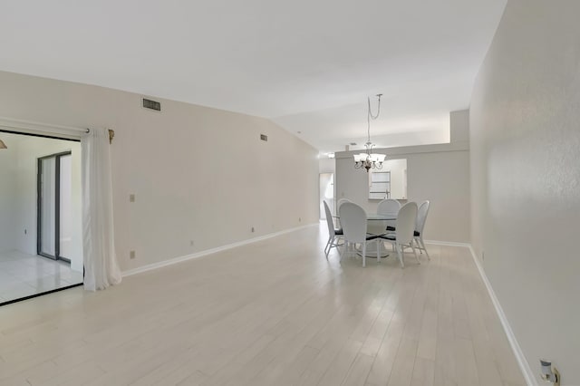 unfurnished dining area featuring light hardwood / wood-style floors, an inviting chandelier, and lofted ceiling