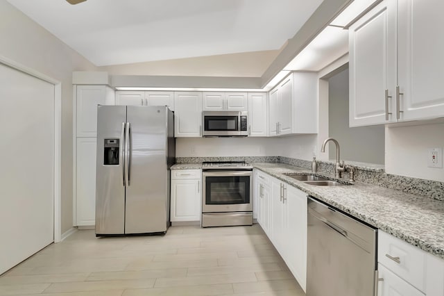 kitchen featuring sink, white cabinetry, stainless steel appliances, and vaulted ceiling