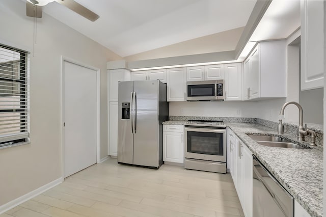 kitchen featuring appliances with stainless steel finishes, vaulted ceiling, sink, light hardwood / wood-style flooring, and white cabinetry