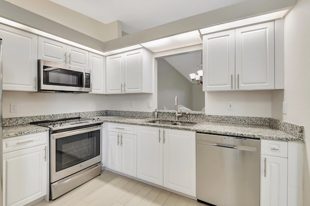 kitchen with a chandelier, sink, white cabinets, and stainless steel appliances