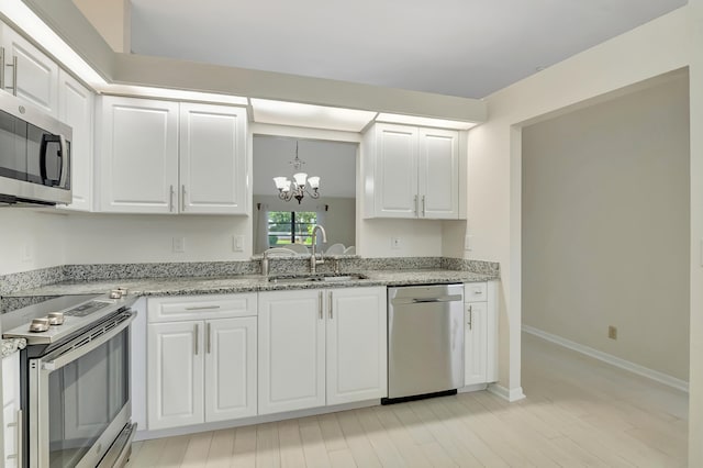 kitchen with white cabinetry, sink, stainless steel appliances, and an inviting chandelier