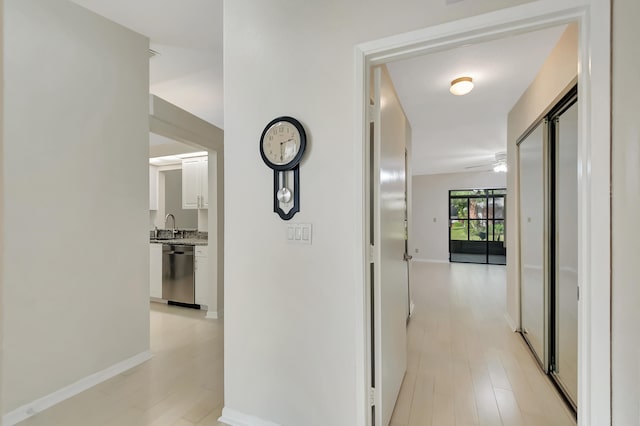 corridor featuring sink and light hardwood / wood-style flooring