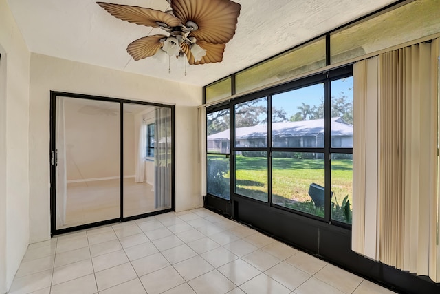 unfurnished sunroom featuring ceiling fan and a healthy amount of sunlight