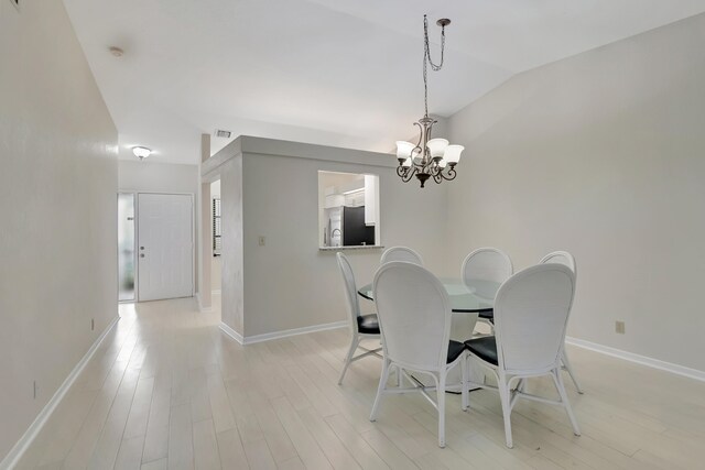 dining space with vaulted ceiling, light hardwood / wood-style flooring, and an inviting chandelier