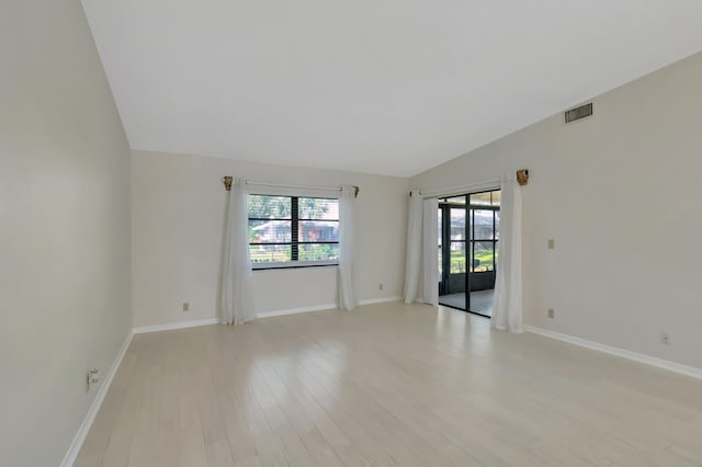 spare room featuring light hardwood / wood-style flooring and lofted ceiling