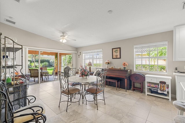 dining space featuring vaulted ceiling, light tile patterned floors, a textured ceiling, and ceiling fan