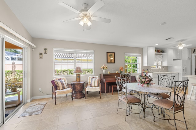 dining space featuring light tile patterned flooring, a healthy amount of sunlight, sink, and ceiling fan