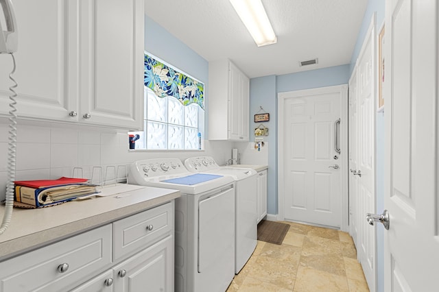 washroom featuring a textured ceiling, cabinets, and washing machine and clothes dryer