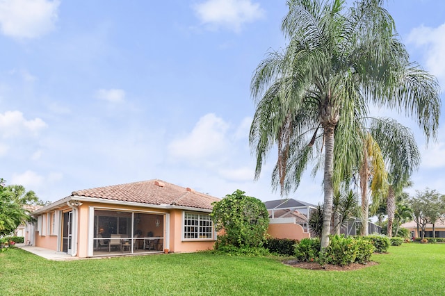 rear view of property featuring glass enclosure and a lawn