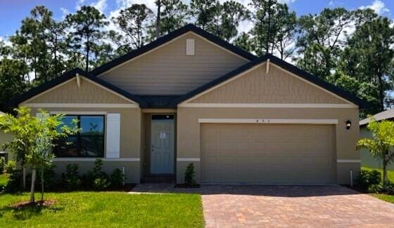 craftsman-style home featuring a garage, decorative driveway, and a front lawn