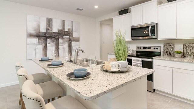kitchen featuring light tile patterned floors, white cabinetry, visible vents, appliances with stainless steel finishes, and a sink