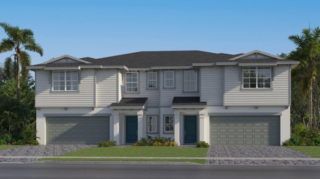 view of front facade featuring a garage, decorative driveway, a front lawn, and stucco siding