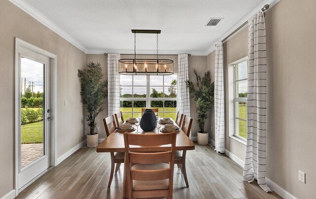 dining room featuring a chandelier, wood tiled floor, visible vents, and ornamental molding