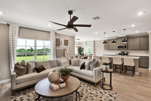 living area featuring ornamental molding, recessed lighting, visible vents, and light wood-style floors