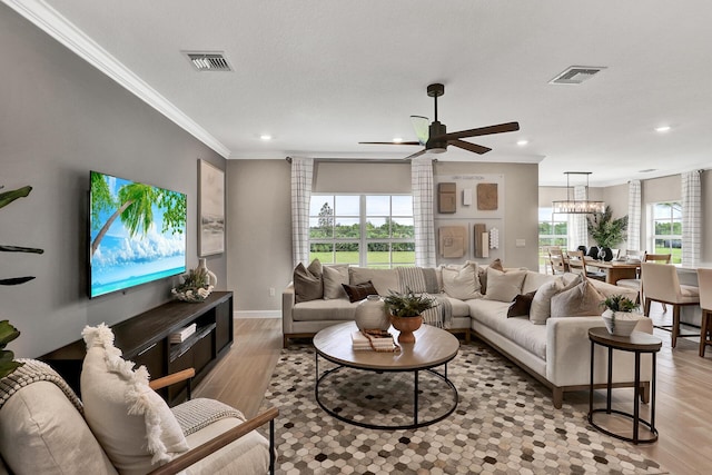 living area with baseboards, light wood-type flooring, visible vents, and crown molding