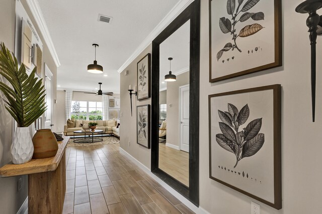 corridor with baseboards, visible vents, crown molding, and wood finish floors