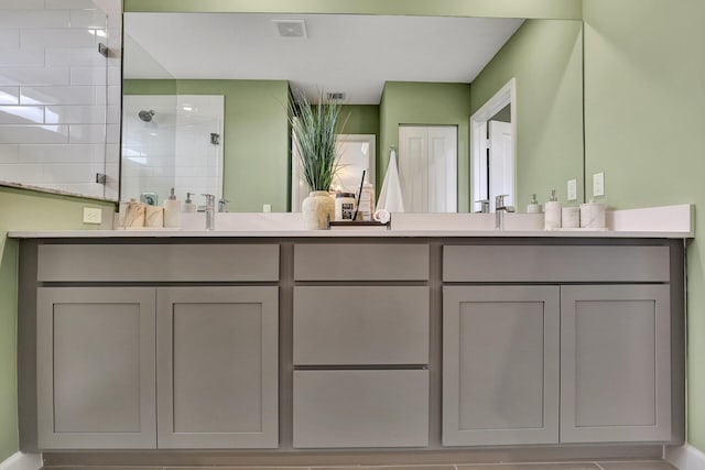 bathroom featuring double vanity, visible vents, a sink, and a walk in shower