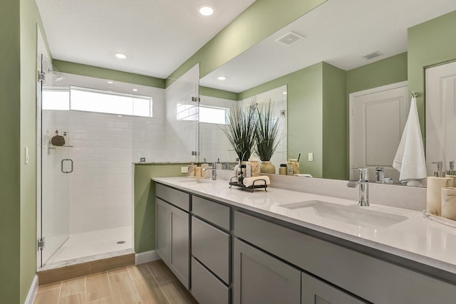 full bathroom with a stall shower, visible vents, a sink, and double vanity