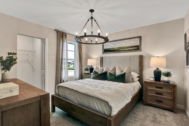 bedroom with carpet floors, a walk in closet, and an inviting chandelier