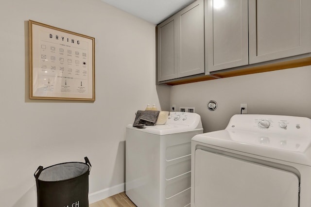 washroom featuring light wood-type flooring, cabinet space, baseboards, and washing machine and clothes dryer