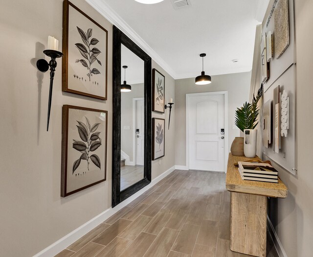 corridor with ornamental molding, light wood-type flooring, and baseboards