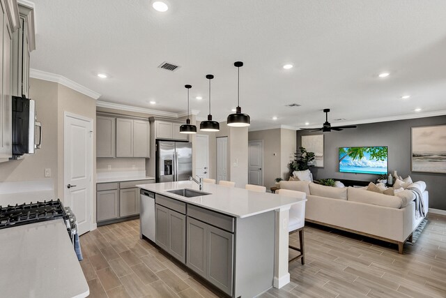 kitchen featuring stainless steel appliances, a sink, visible vents, gray cabinets, and wood tiled floor