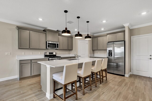 kitchen with gray cabinetry, stainless steel appliances, wood finish floors, a sink, and visible vents