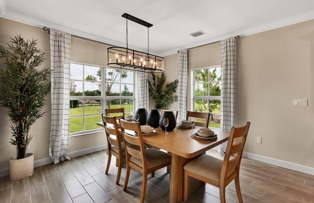 dining area featuring baseboards, visible vents, crown molding, wood finish floors, and a chandelier