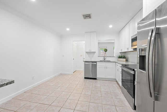 kitchen featuring light stone countertops, appliances with stainless steel finishes, backsplash, light tile patterned floors, and white cabinetry