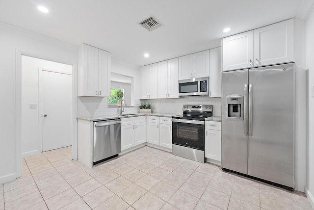 kitchen featuring light stone countertops, stainless steel appliances, sink, light tile patterned floors, and white cabinets