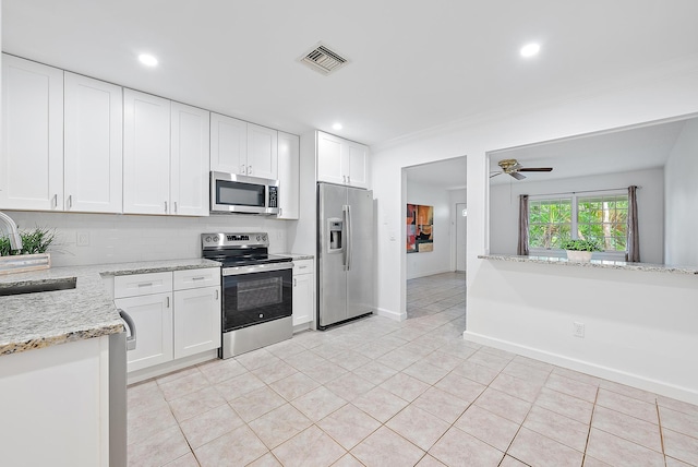 kitchen featuring light stone countertops, stainless steel appliances, sink, white cabinetry, and light tile patterned flooring