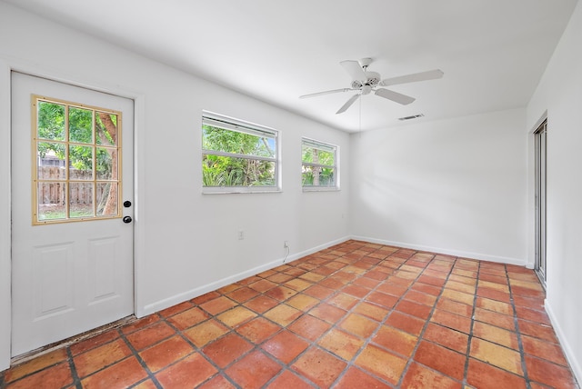 empty room featuring tile patterned flooring, ceiling fan, and a healthy amount of sunlight