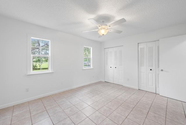 unfurnished bedroom with multiple windows, ceiling fan, and light tile patterned floors