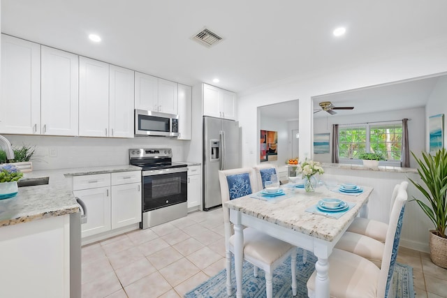 kitchen featuring light stone countertops, a kitchen breakfast bar, stainless steel appliances, sink, and white cabinetry