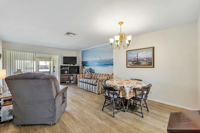 dining space featuring light hardwood / wood-style floors and an inviting chandelier