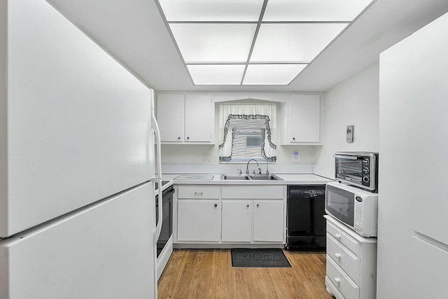 kitchen with white cabinets, light hardwood / wood-style floors, white appliances, and sink