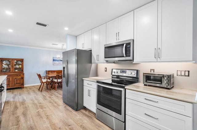 kitchen with light wood-type flooring, white cabinetry, crown molding, and appliances with stainless steel finishes