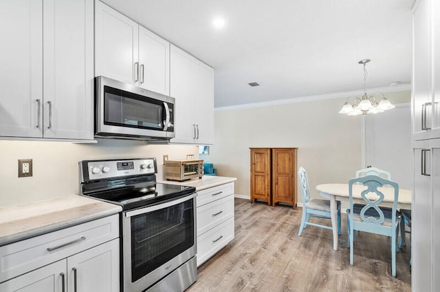 kitchen with light wood-type flooring, stainless steel appliances, crown molding, pendant lighting, and white cabinets