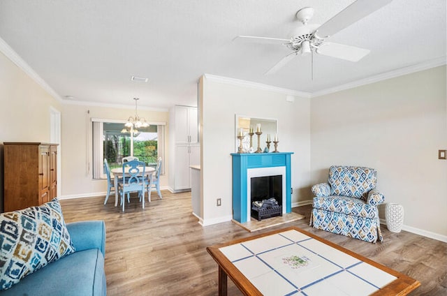 living room featuring crown molding, ceiling fan with notable chandelier, and hardwood / wood-style flooring