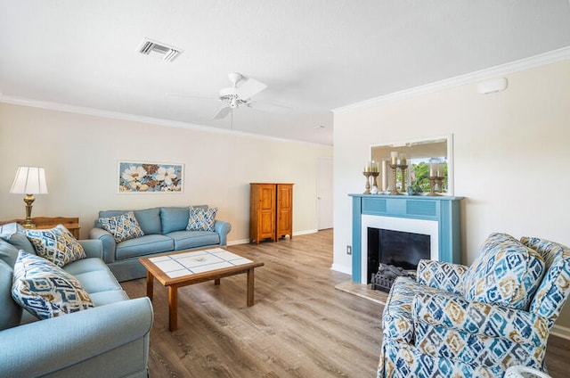 living room with hardwood / wood-style floors, ceiling fan, and ornamental molding