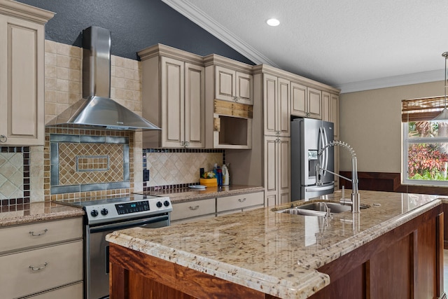 kitchen with lofted ceiling, cream cabinets, wall chimney range hood, and appliances with stainless steel finishes