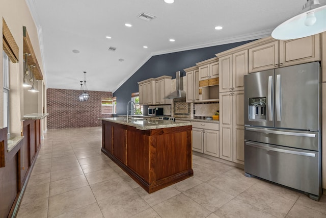 kitchen featuring stainless steel fridge with ice dispenser, brick wall, a kitchen island with sink, cream cabinetry, and wall chimney exhaust hood