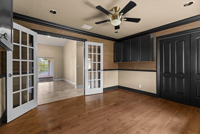 empty room featuring hardwood / wood-style flooring, a textured ceiling, ornamental molding, and french doors