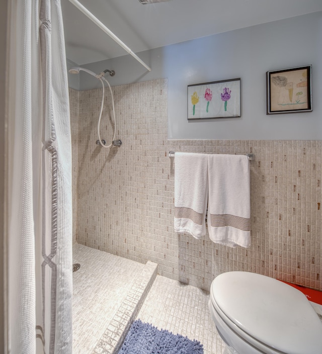 bathroom with a shower with curtain, toilet, and tile walls