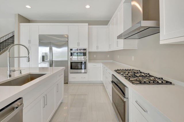 kitchen with white cabinetry, sink, wall chimney range hood, and appliances with stainless steel finishes