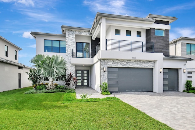 modern home with a garage, a balcony, a front yard, and french doors