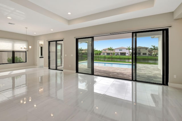 tiled spare room with a tray ceiling and plenty of natural light