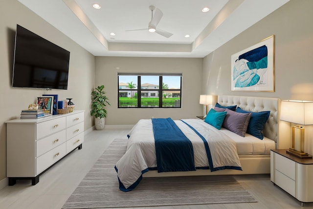 bedroom with ceiling fan and a tray ceiling