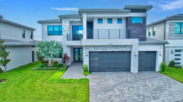 view of front of property with a balcony, a front yard, and a garage